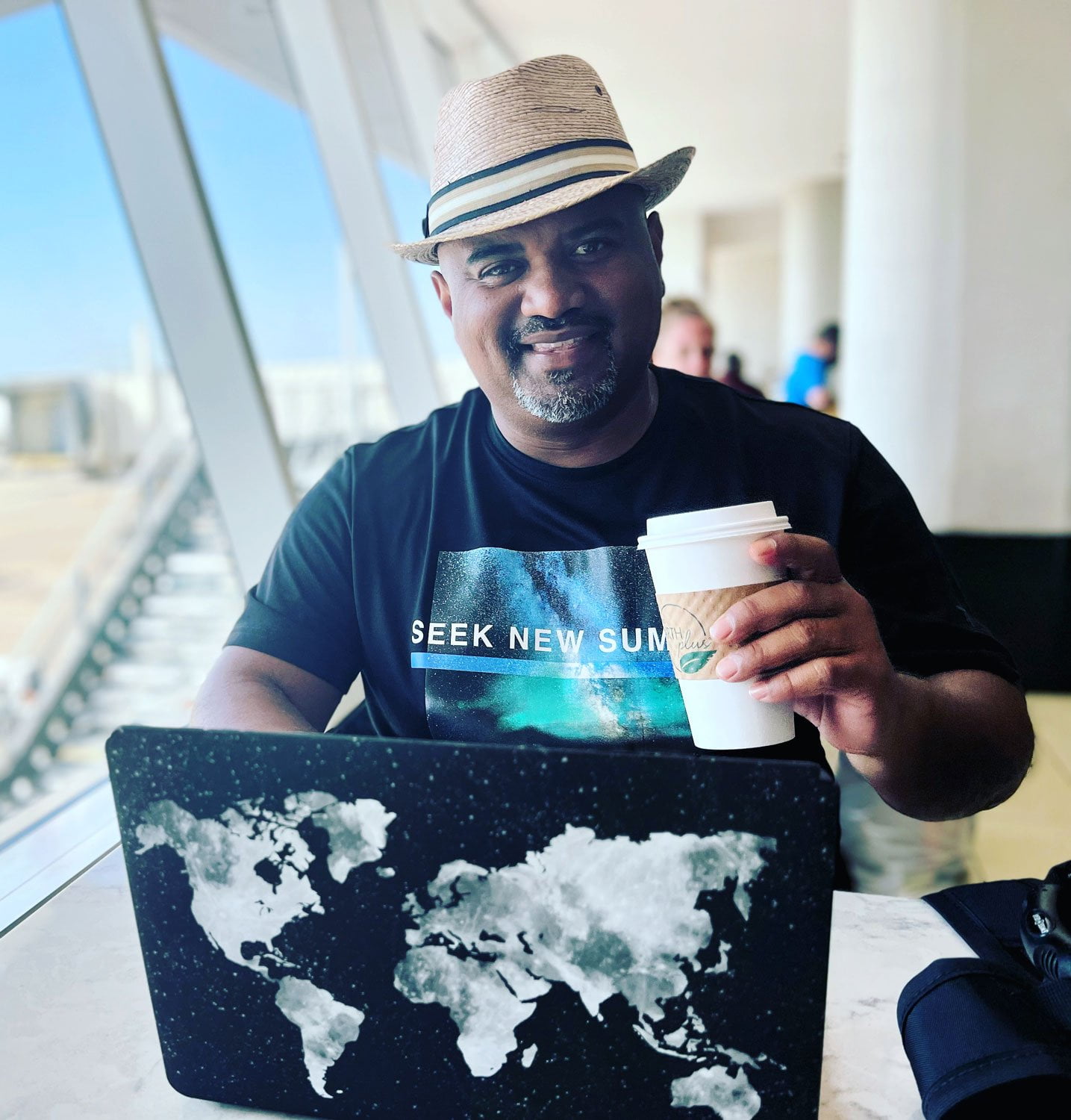 A man, one of the digital marketing experts, in a hat holding a cup of coffee.