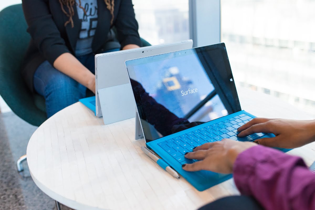 Two people sitting at a table using a Microsoft Surface Pro to discuss which browser is best.