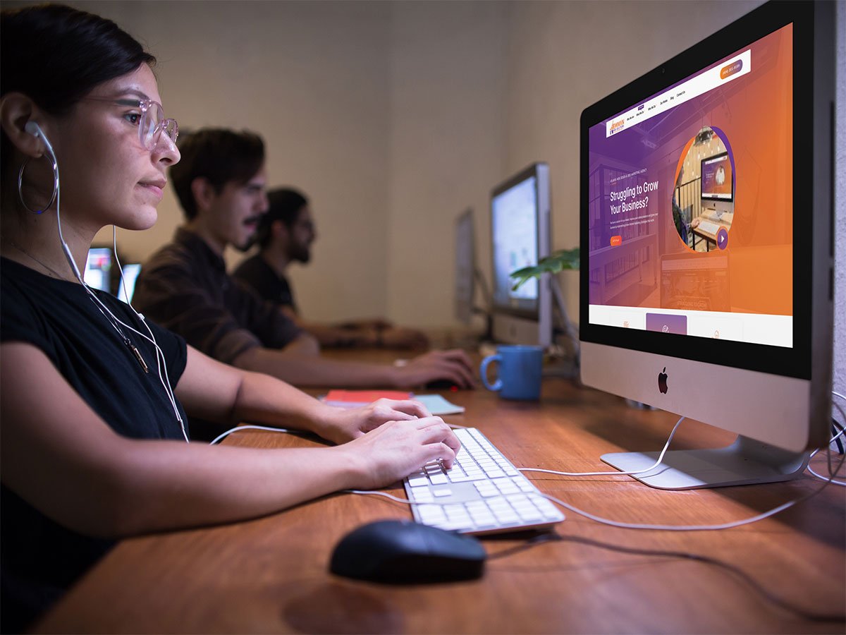 A website support expert for Newman Web Solutions Agency is sitting in front of a computer, browsing local business web design services for small businesses.