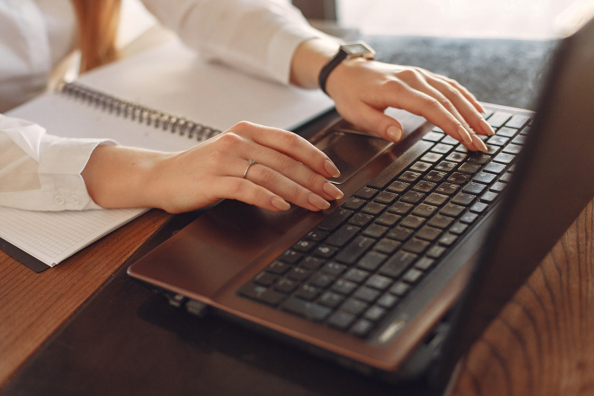 A woman typing on a laptop keyboard to understand what is alt text.