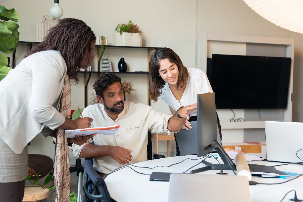 Three people in a marketing agency office looking at a computer screen.