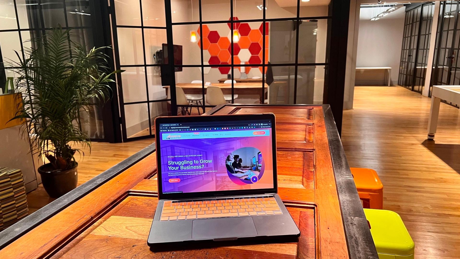 A laptop sits on a wooden table in an office, showcasing the services of a local SEO company.