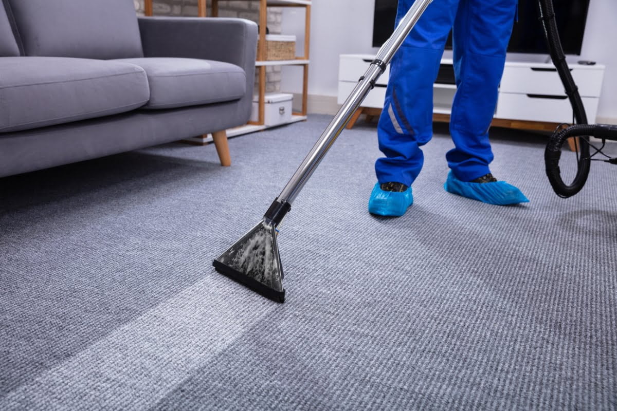 A man cleaning a carpet in a living room for an advertisement promoting carpet cleaning services.