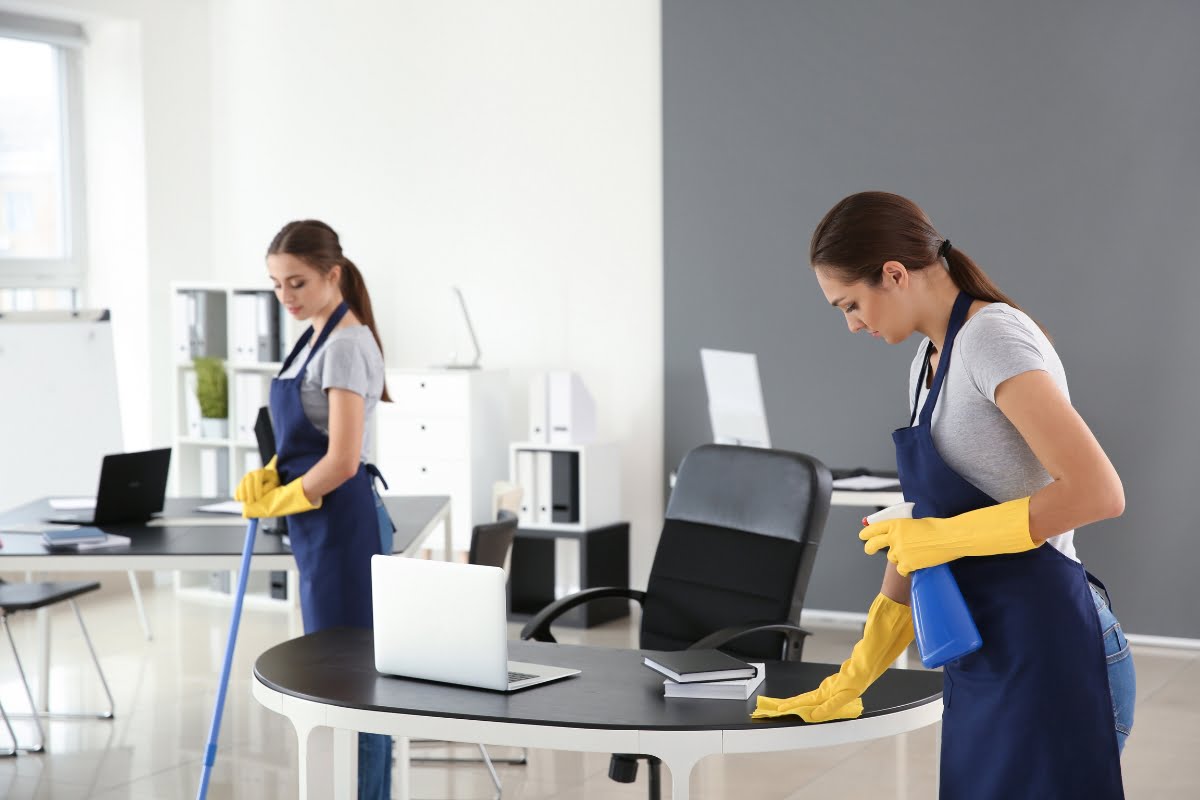 Two women in aprons cleaning an office with advertising ideas.