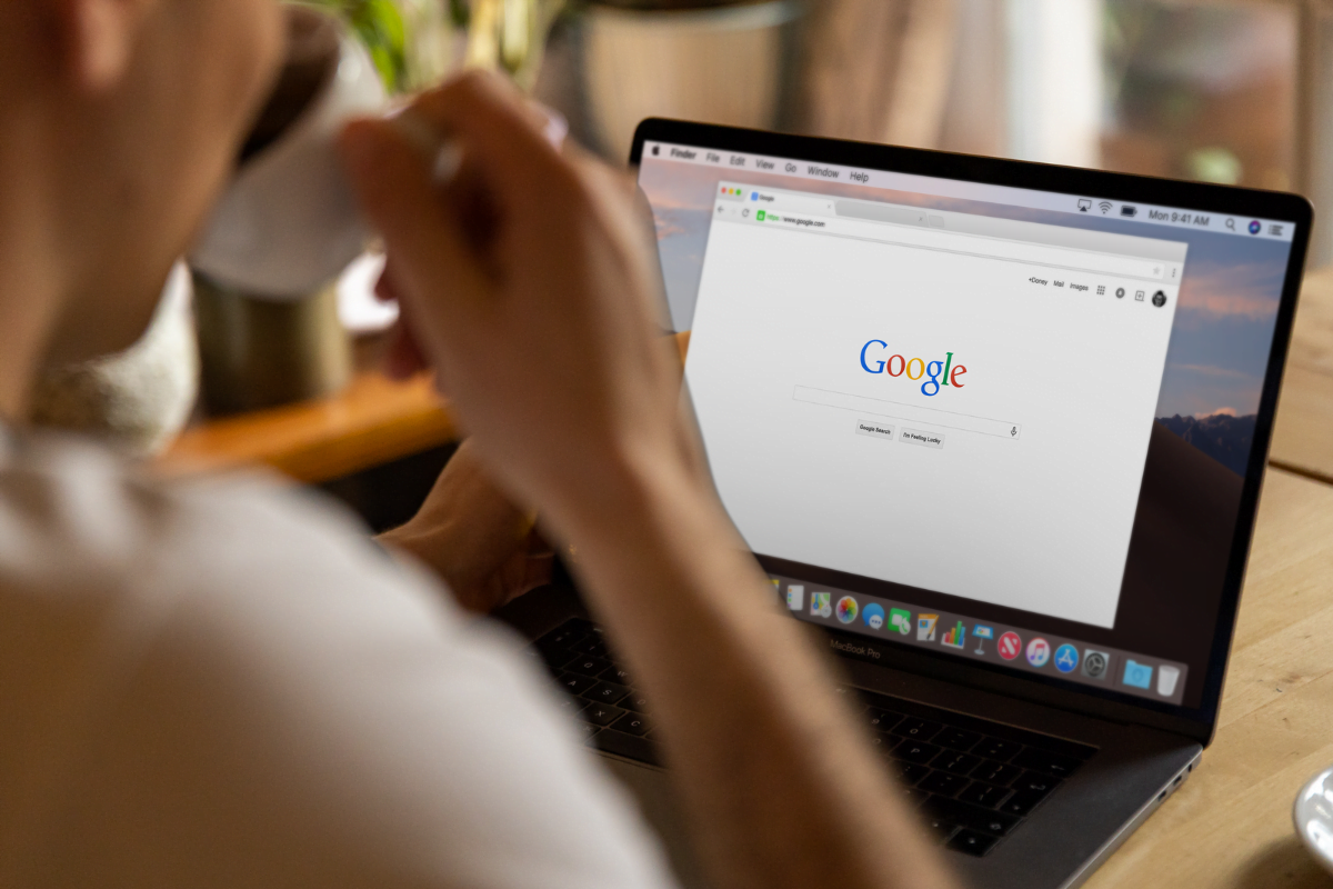 A man is looking at a laptop with Google search on it.