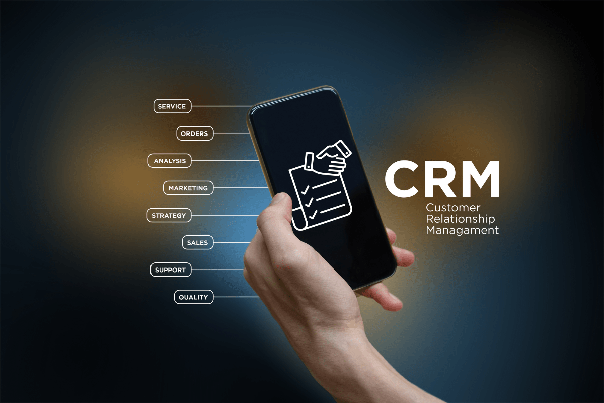 A hand holding a smartphone with the word "CRM" displayed for marketing CRM software.