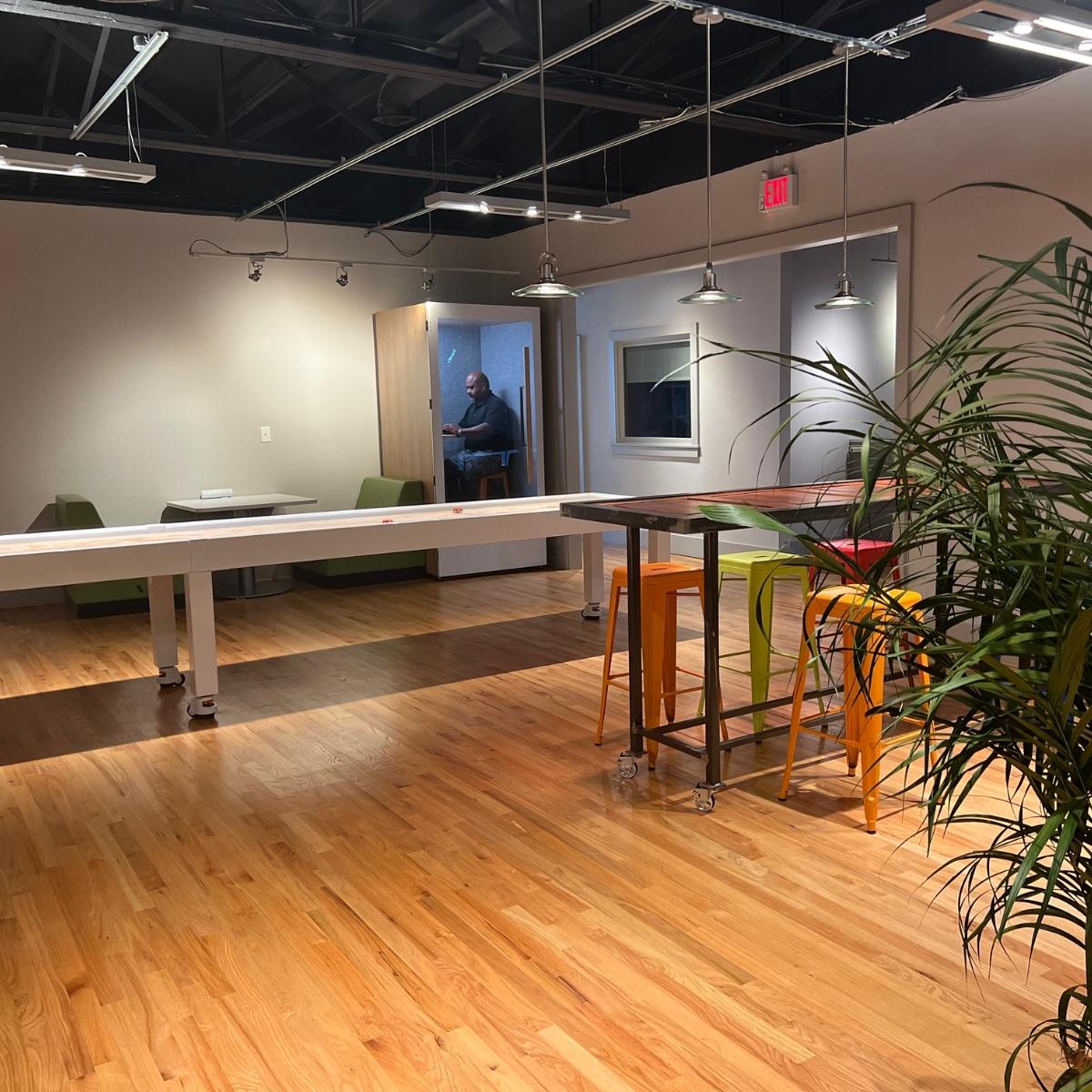 An office with a table and chairs and a plant designed by Milton.