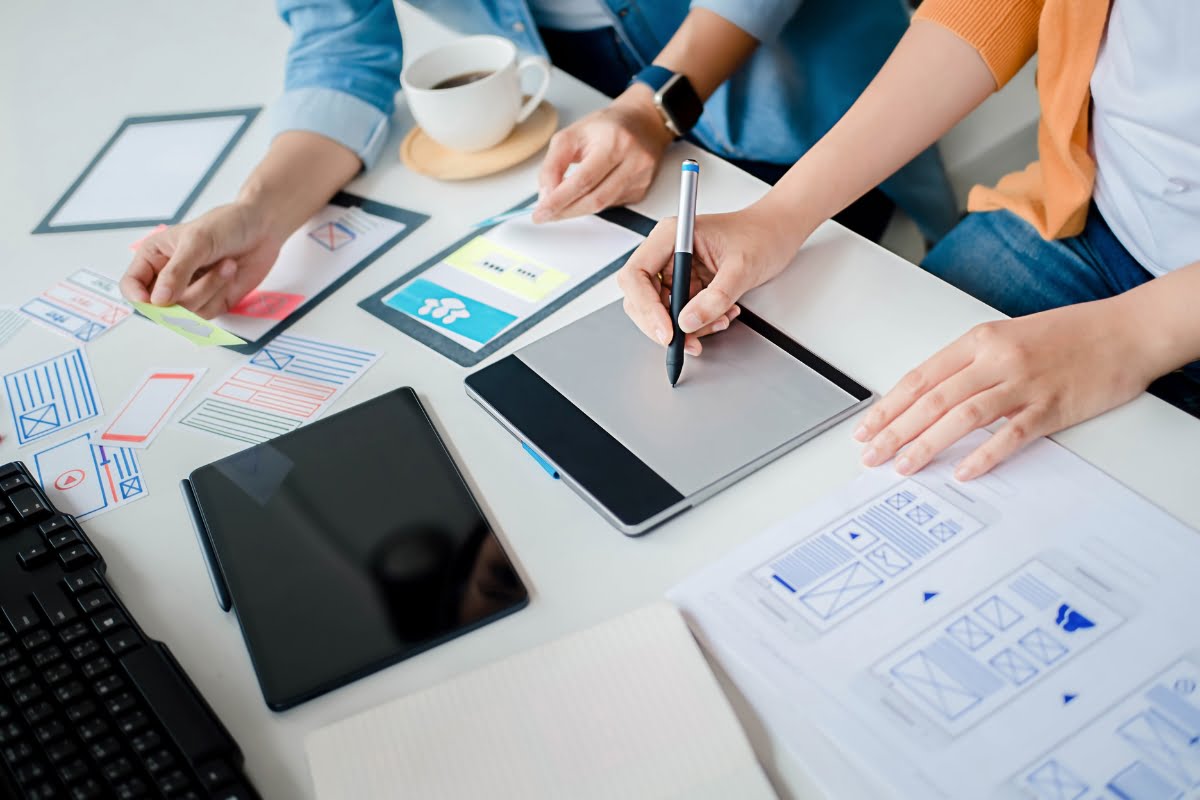 A group of people working at a desk with paper and pens, collaborating on a content marketing strategy.