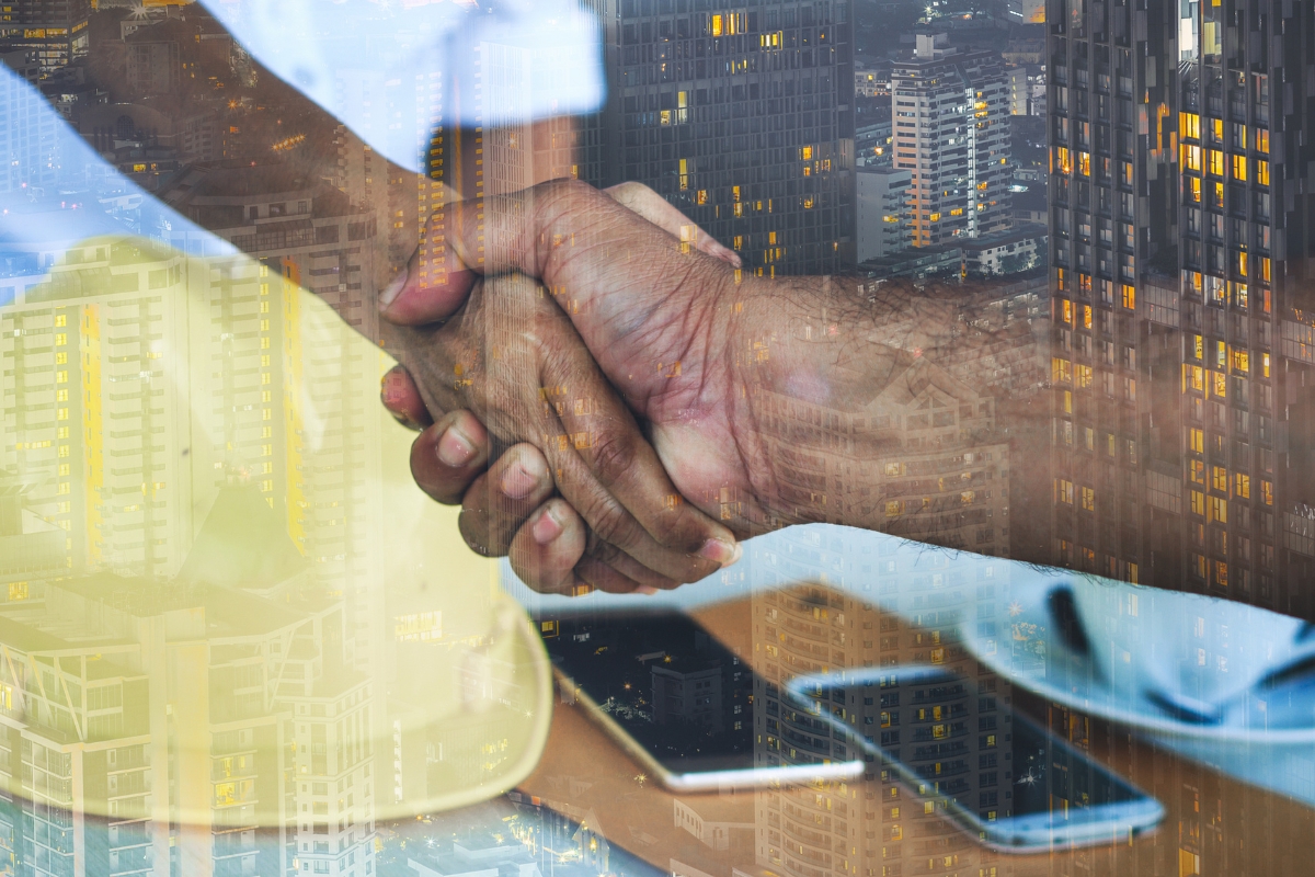 Two people shaking hands superimposed on an urban skyline at dusk, symbolizing marketing for construction companies.