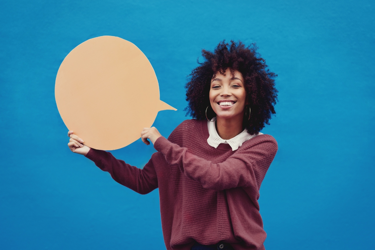 Woman holding a "word of mouth marketing" speech bubble against a blue background.