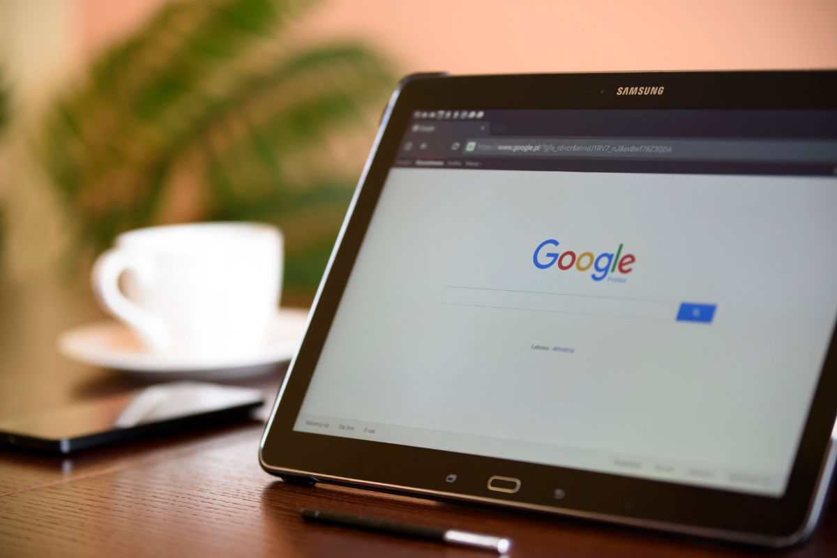 A tablet displaying the Google Guaranteed local services search homepage on a desk next to a coffee cup.