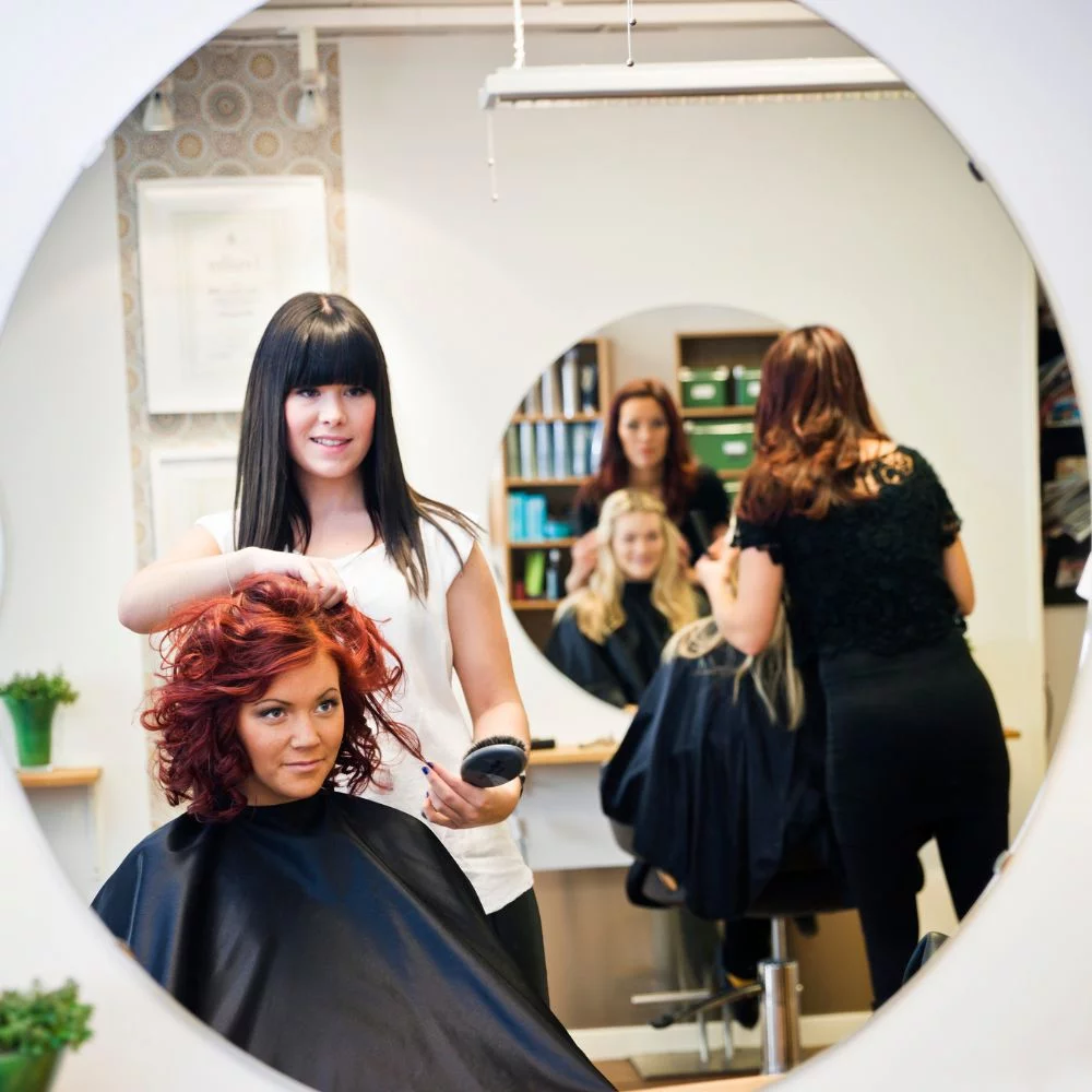 A woman getting her hair cut at a salon.