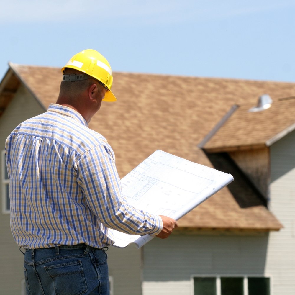 A man utilizing a blueprint to showcase roofing marketing strategies in front of a house.