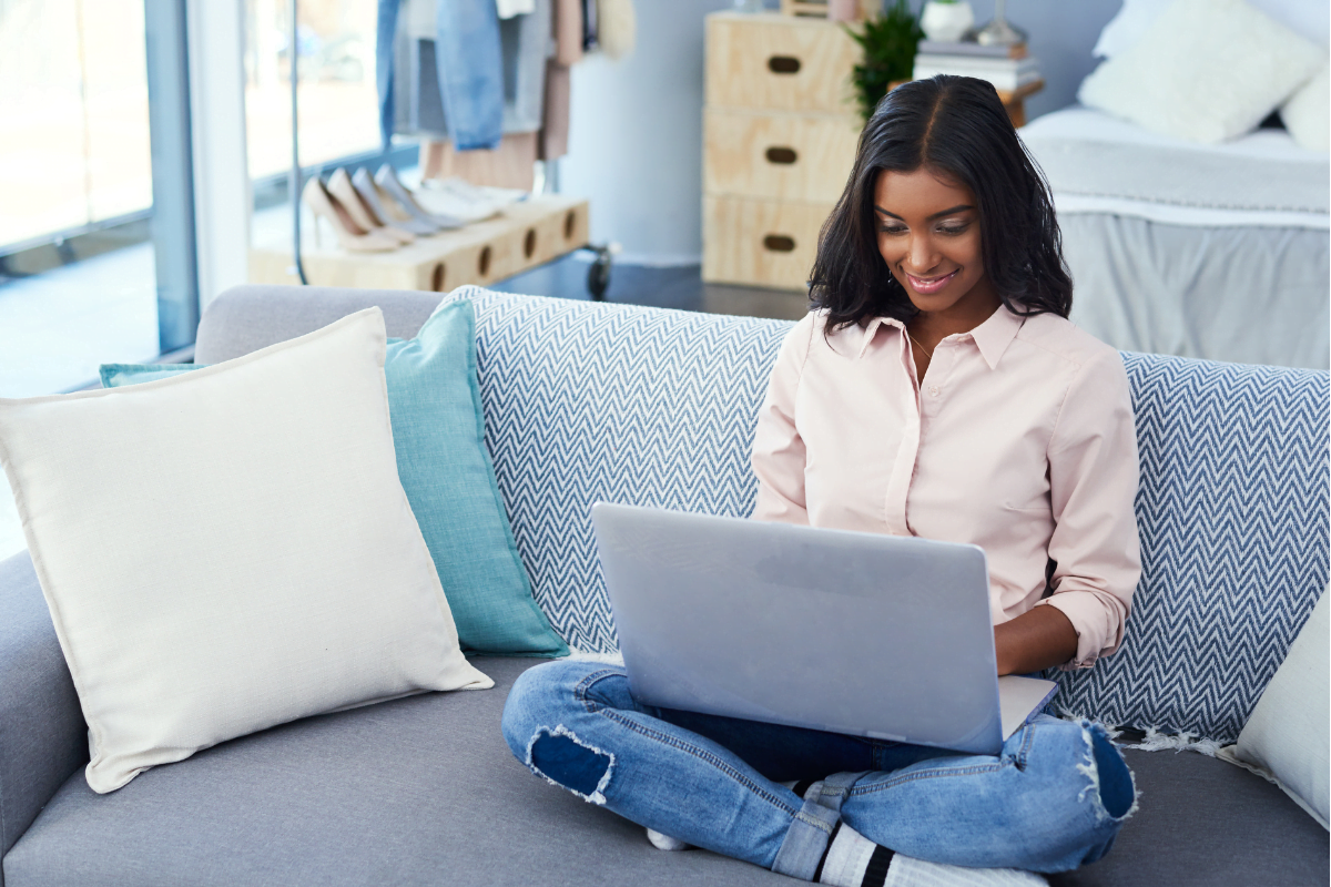 A businesswoman boosting her online presence with her laptop while sitting on a couch.