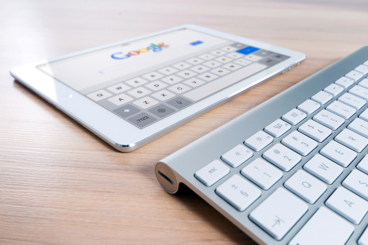 A tablet with a keyboard on a table displaying Google search.