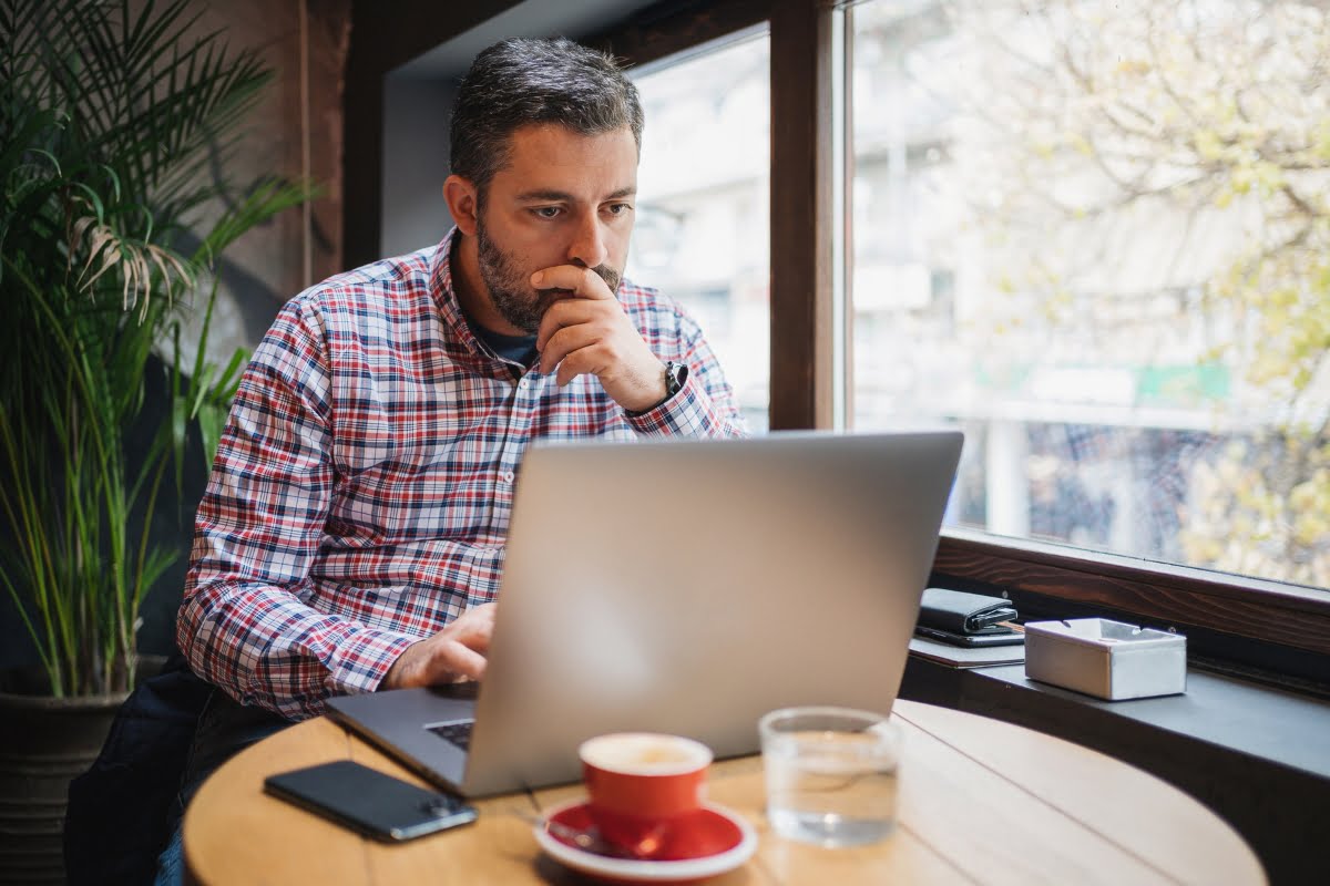 A man analyzing website traffic sources with a laptop and a cup of coffee on the table.