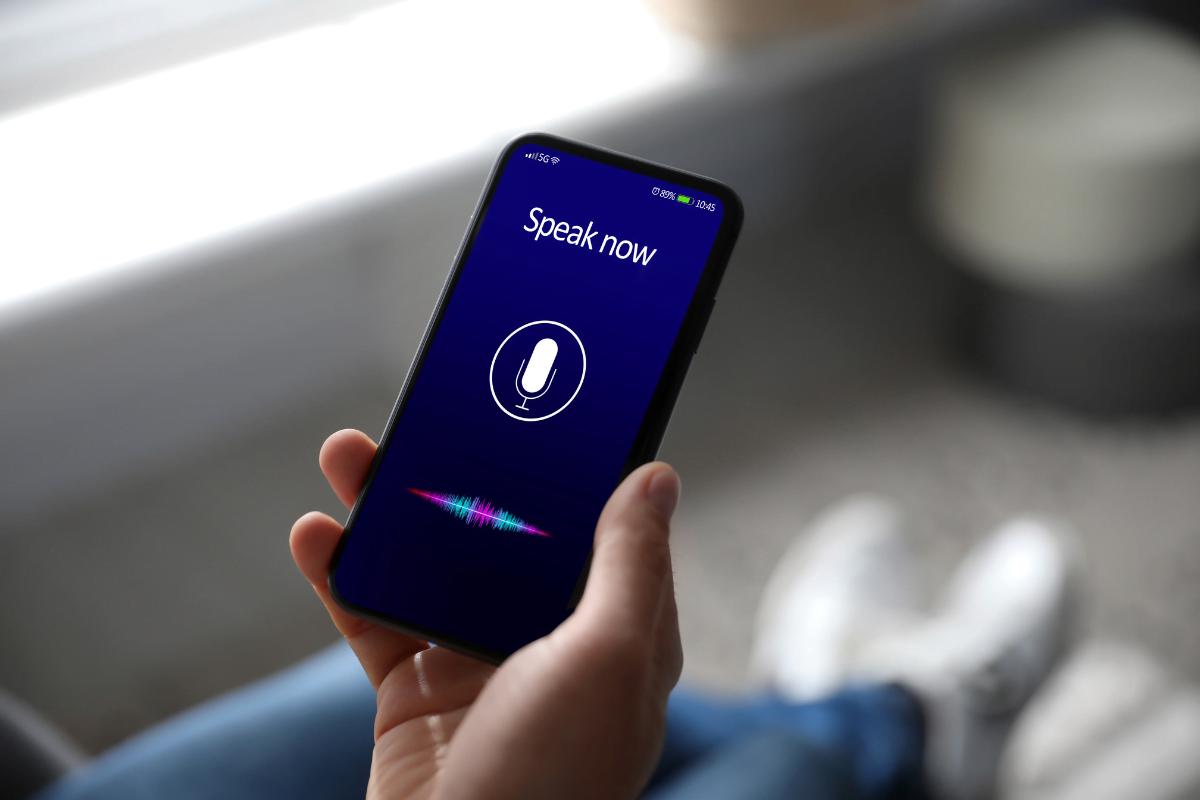 A person interacting with a smartphone displaying a voice search.
