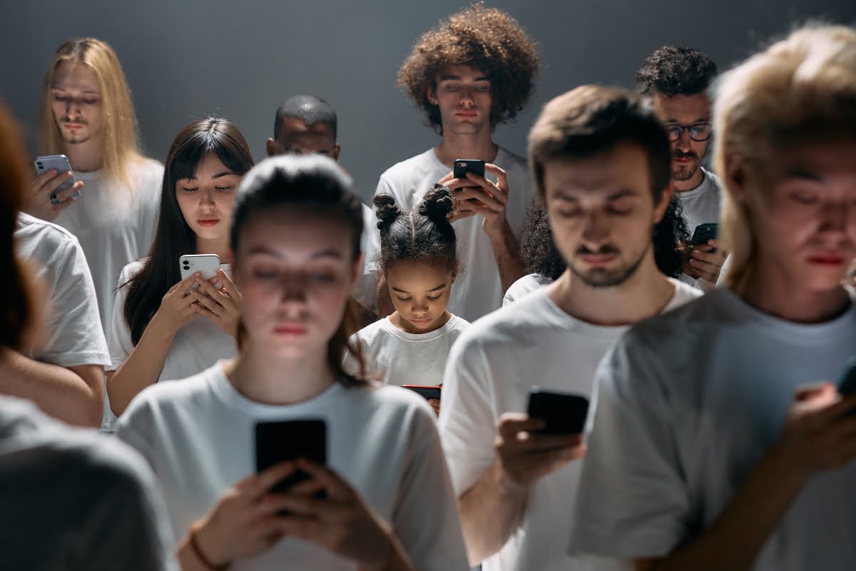 A group of people in white t-shirts are looking at their phones, unaware of the shadow banning.