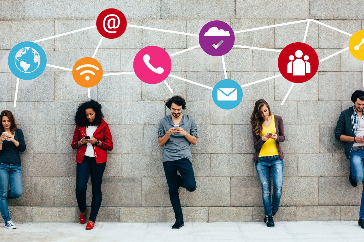 A group of people standing in front of a wall adorned with social media icons, symbolizing the intersection of technology, social media and relationships.