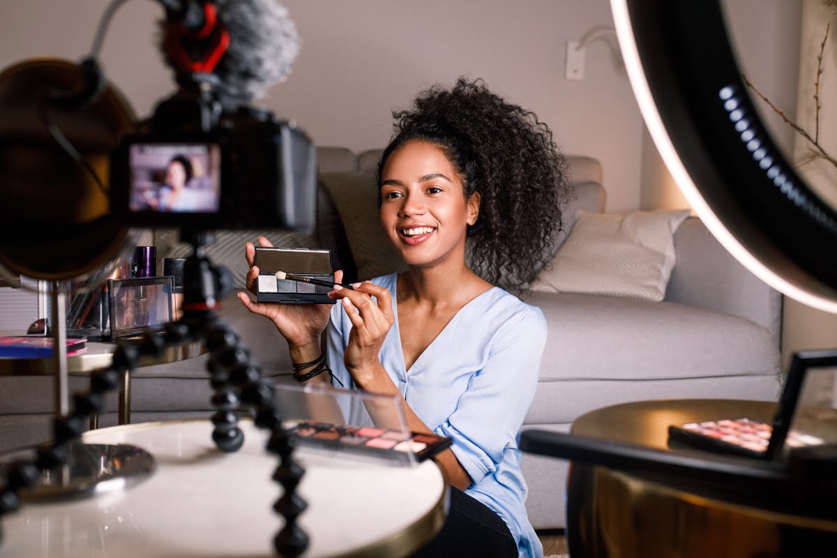 A young woman capturing construction marketing strategy moments with a camera while showcasing makeup products.