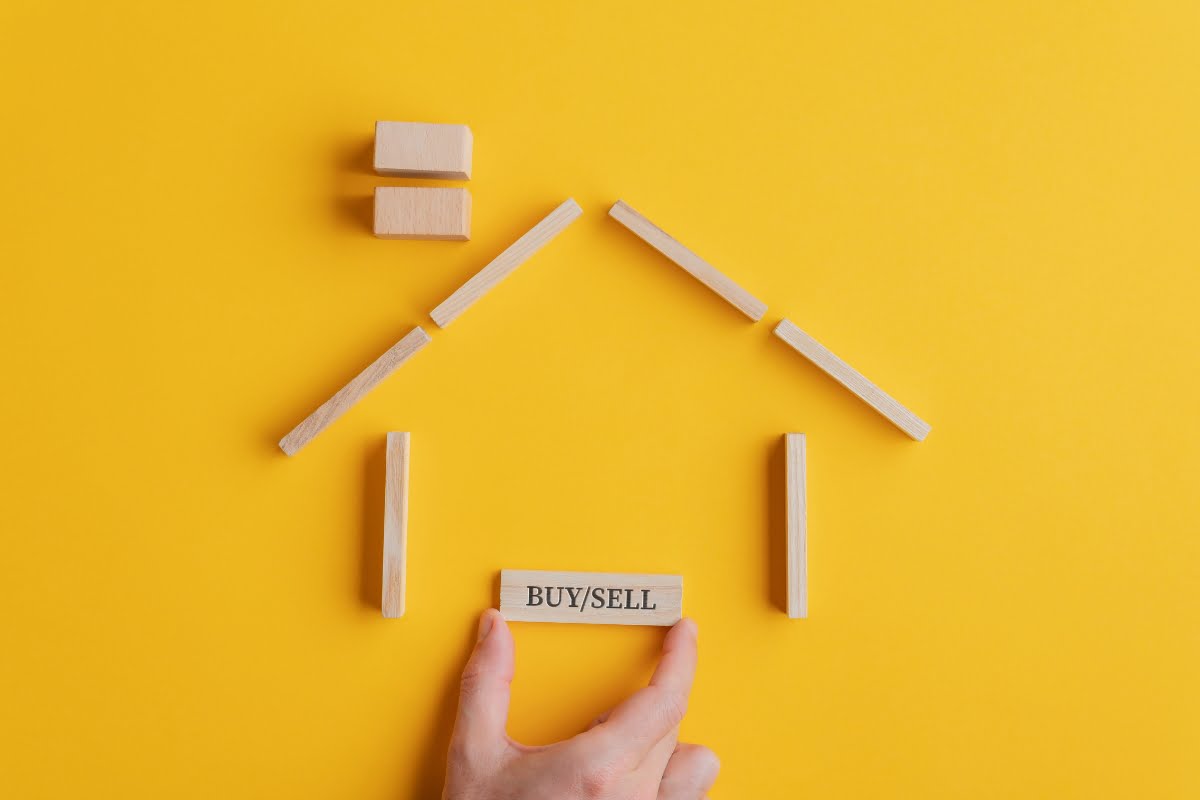 A hand holding a wooden house as part of a construction marketing strategy.