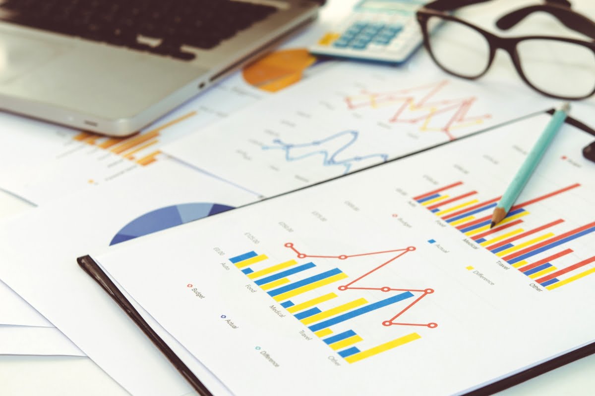 A clipboard with data-driven graphs and a laptop on it.