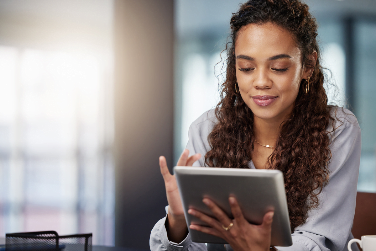 A woman using a tablet computer for email automation workflows in an office.