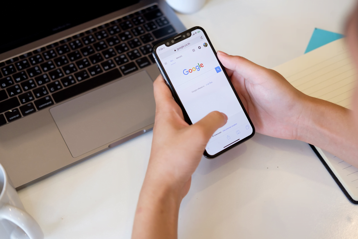 A person holding a phone with Google displayed on the screen.