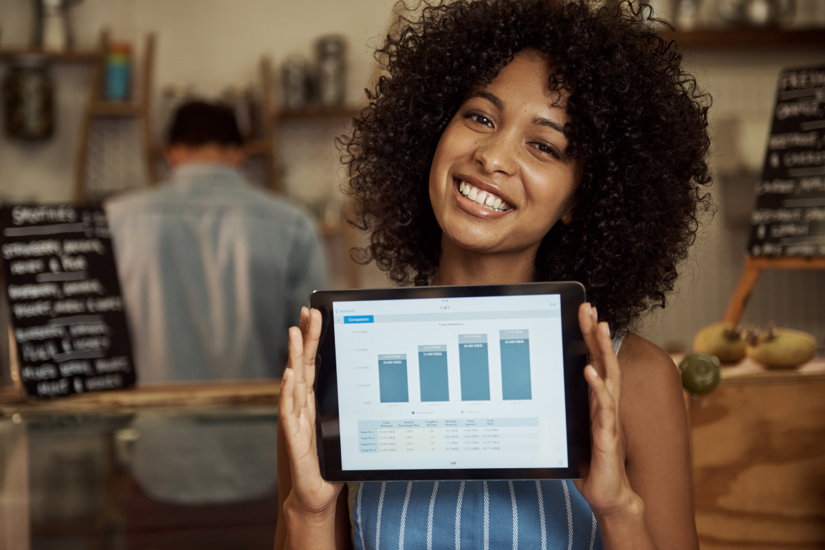 A woman is holding up a tablet displaying a graph of her business growth.