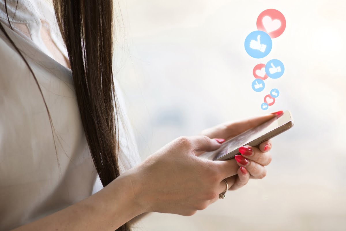 A woman holding a cell phone with social icons and link shorteners on it.