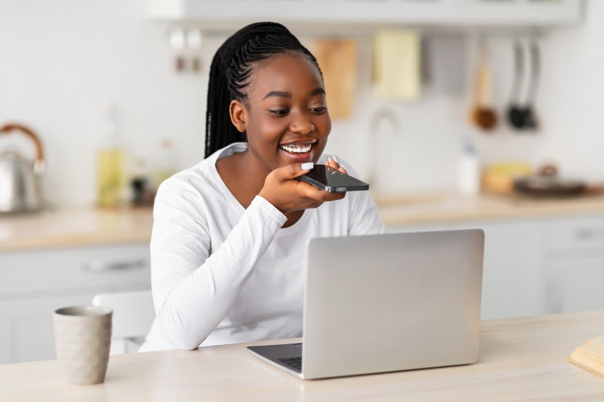 A young woman using a laptop for voice search.