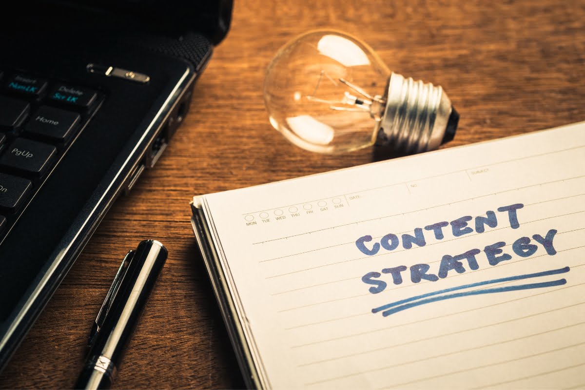 A notebook with the word content strategy next to a light bulb, illustrating the importance of a strategic approach to creating and managing content on WordPress.