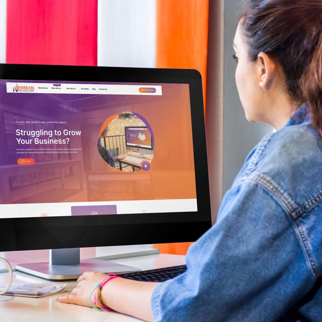 A Newman Web Solutions web designer sitting in front of a computer screen, browsing the Atlanta web design company's website, who specializes in Local Business Web Design Services For Small Businesses.