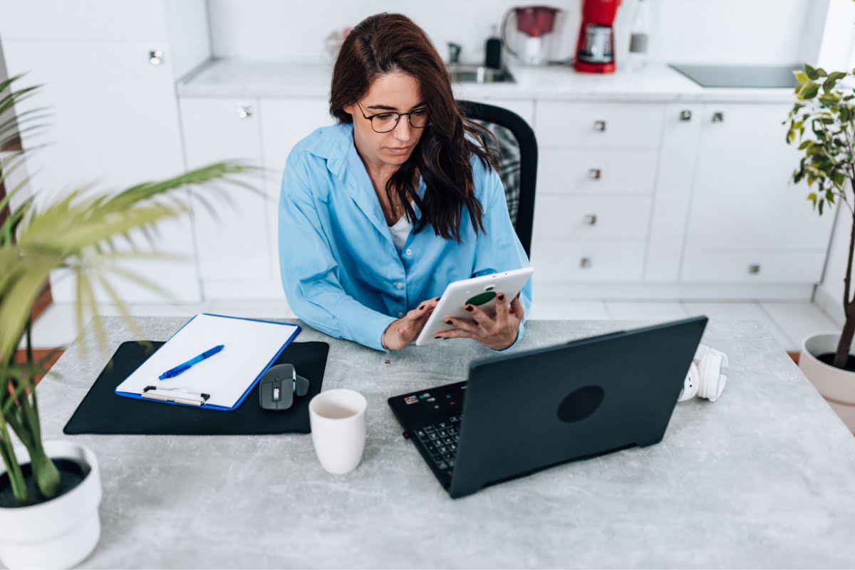 A woman sitting at a desk using a laptop to fix business profiles.