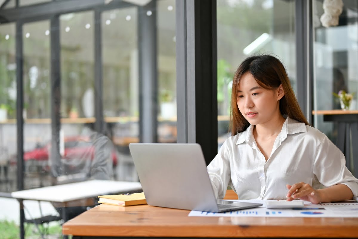 Businesswoman fixing suspended business profiles on her laptop in a cafe.