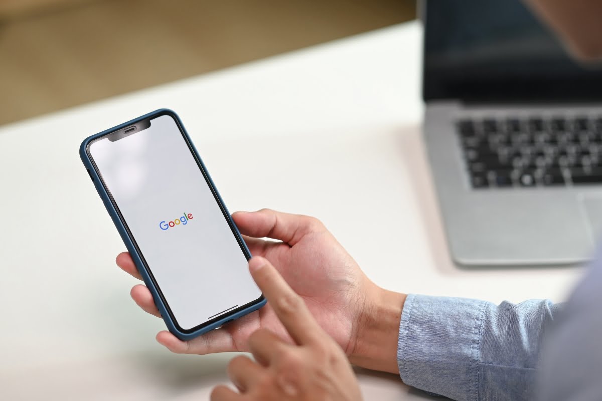 A man holding a phone displaying the Google logo and submitting a reinstatement request for his Google Business profile.