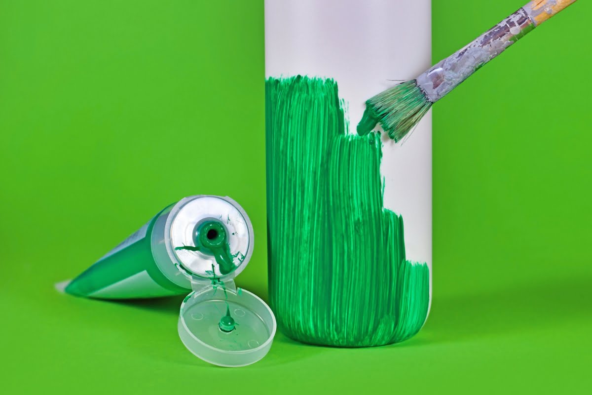 Techniques to avoid greenwashing while using green paint on a bottle with a brush on a green background.