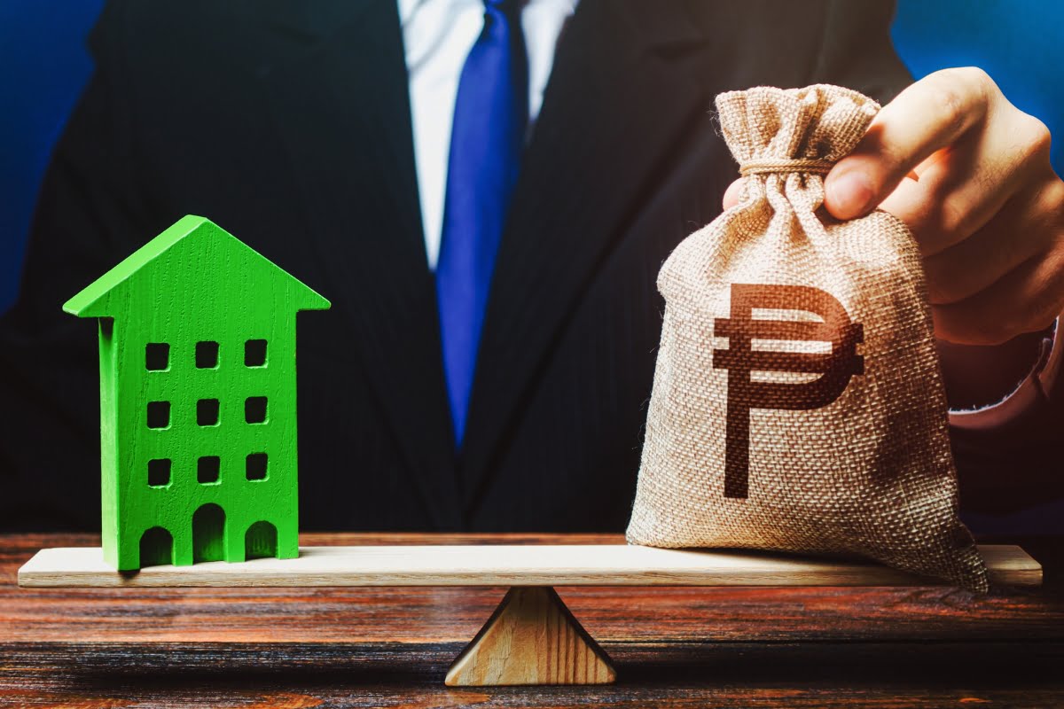 A businessman holding a bag with a house on a sustainable scale.