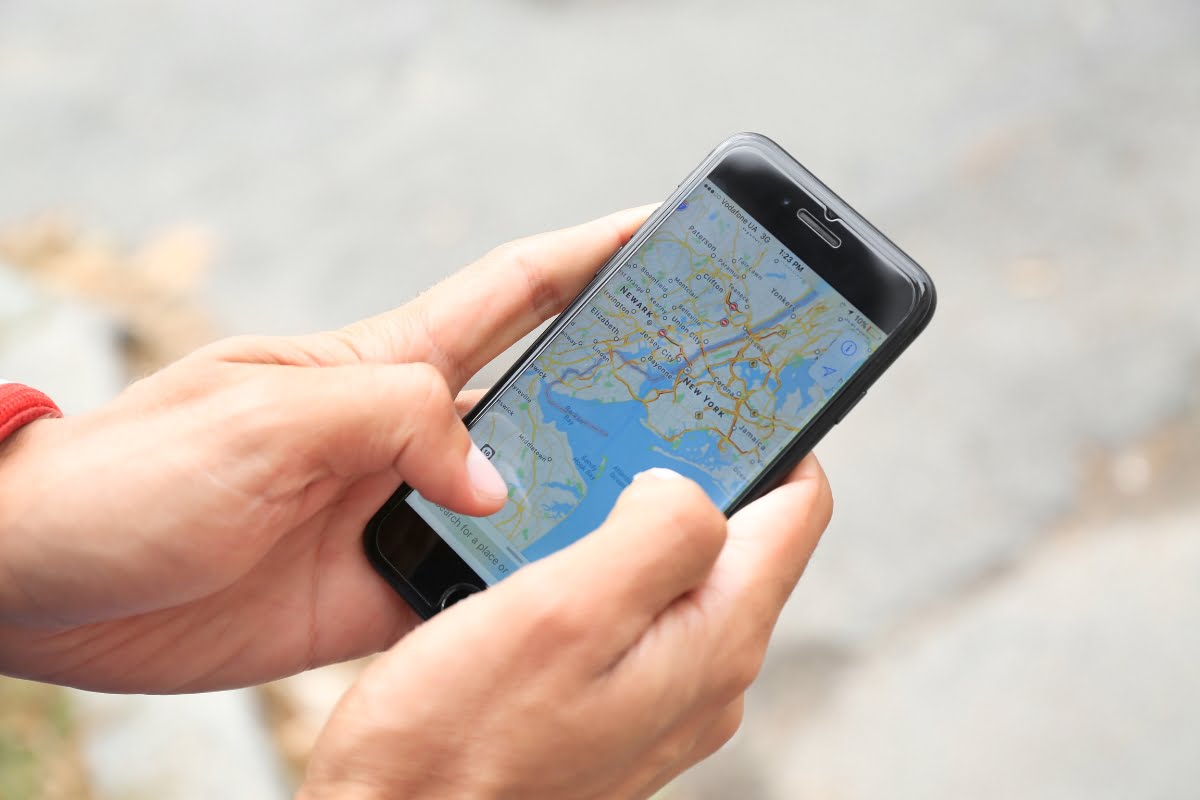 A person holding a smart phone with a map of local businesses on Google Maps.