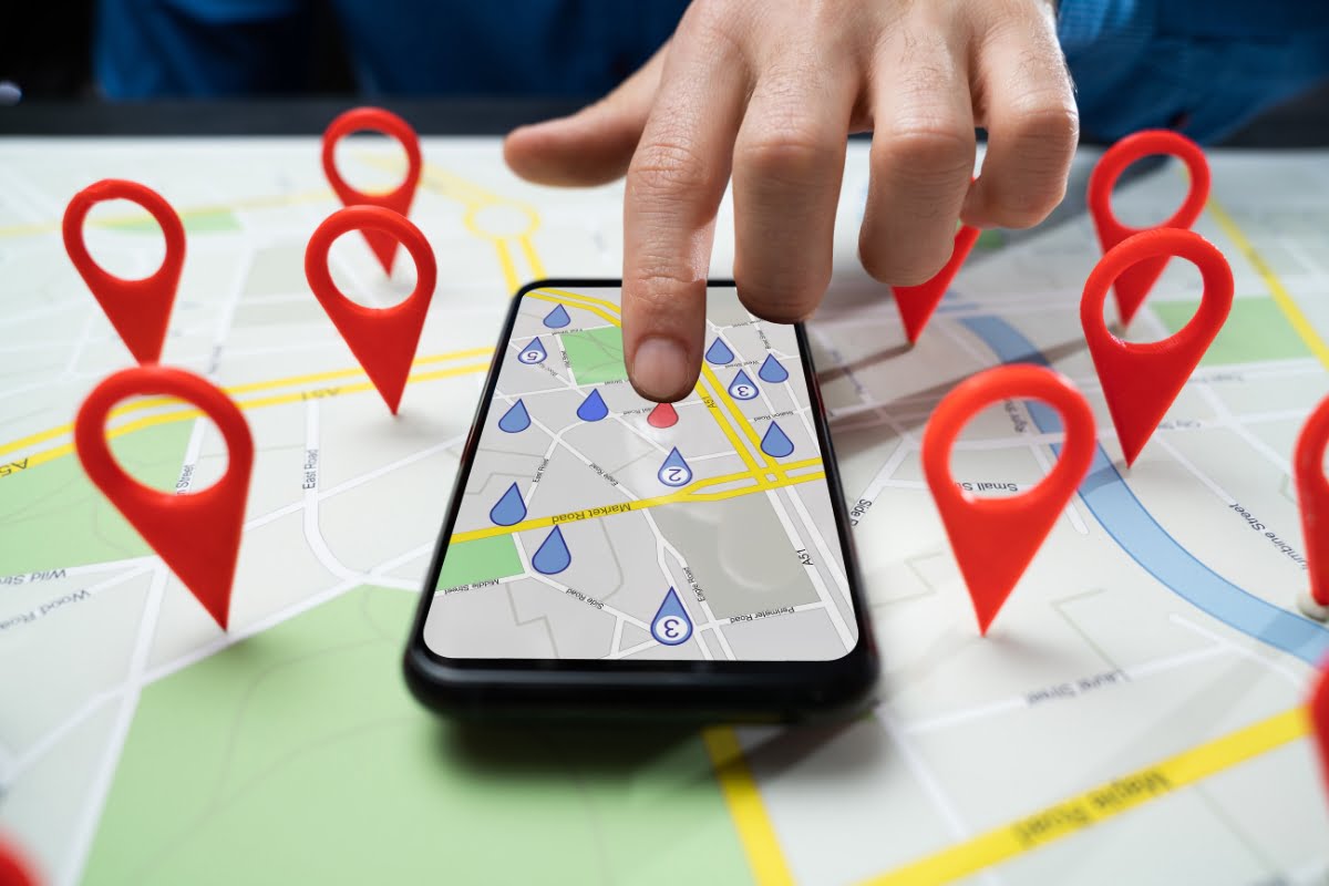 A person holding a phone with pins on a map, exploring local businesses on Google Maps.