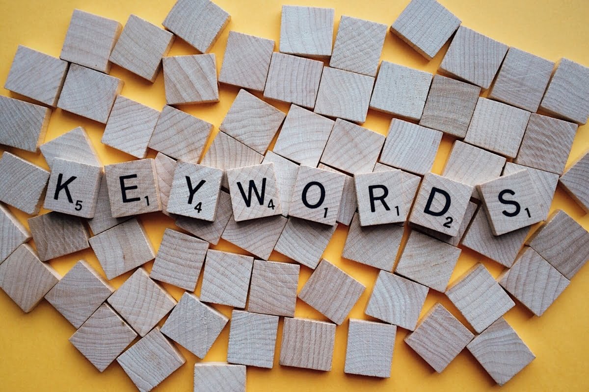 The word "keywords" spelled out in wooden cubes on a yellow background, showcasing effective search engine optimization techniques.