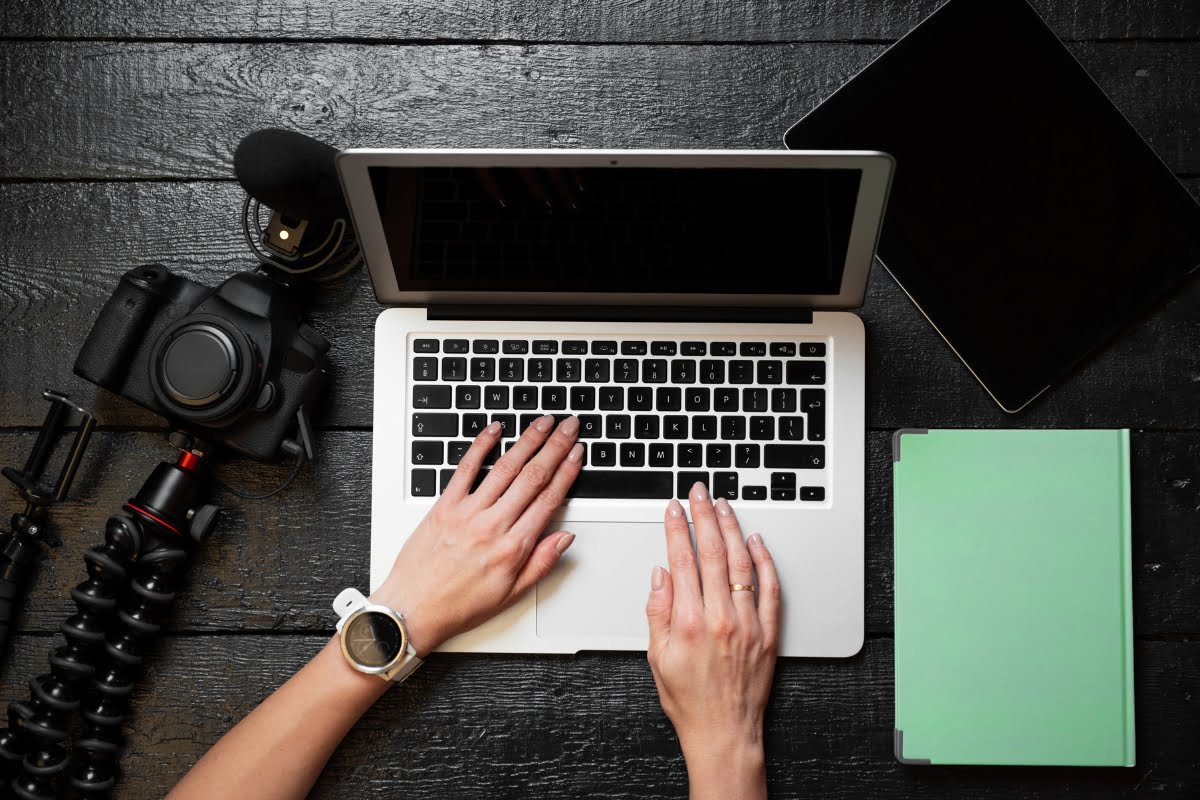 A woman's hands engaging in search engine optimization techniques while typing on a laptop placed on a wooden table.