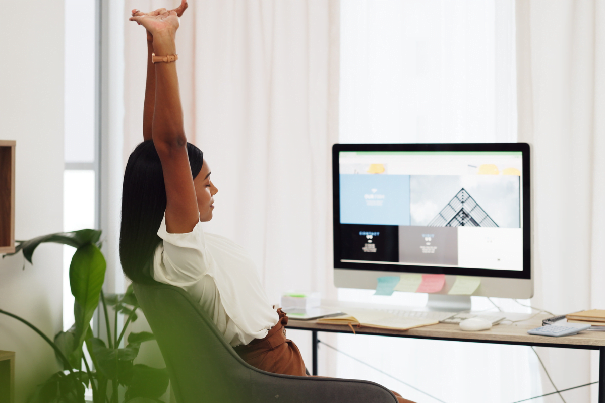 A woman raising her arms in front of a computer screen, demonstrating the benefits of using WordPress.