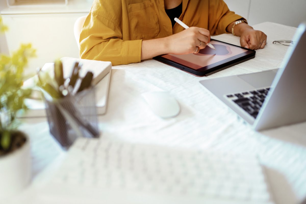 A woman sitting at a desk in a boutique agency, with a laptop and a pen.