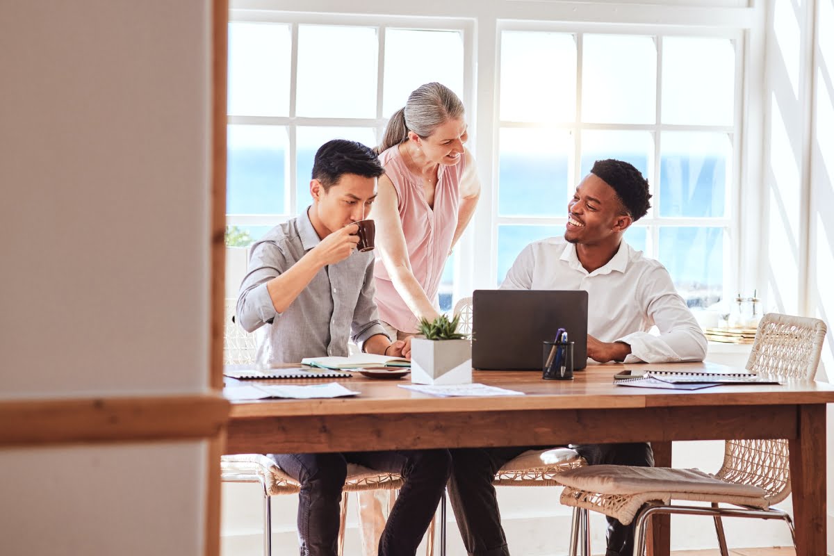 A boutique agency of people sitting around a table with laptops.