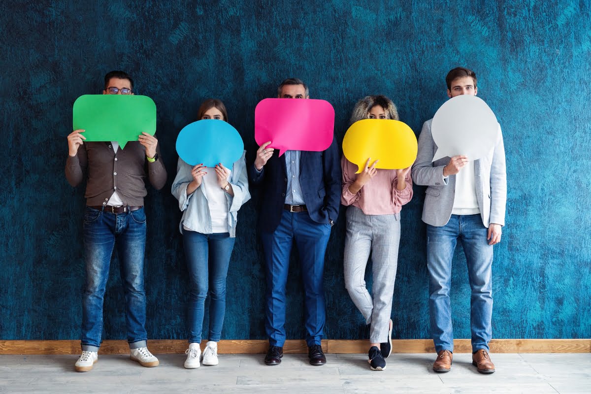 A boutique agency showcases a group of people holding colored speech bubbles in front of a blue wall.