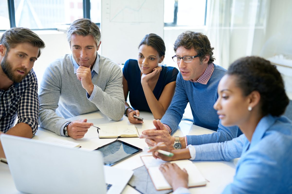 A boutique agency consisting of a select group of individuals sitting around a table, all focused on the laptop screen.