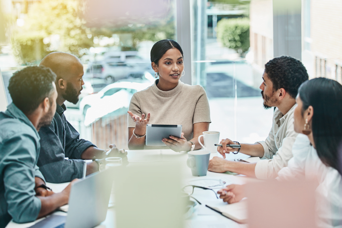 A group of people from digital marketing agencies for startups sitting around a table in a meeting, discussing strategies.