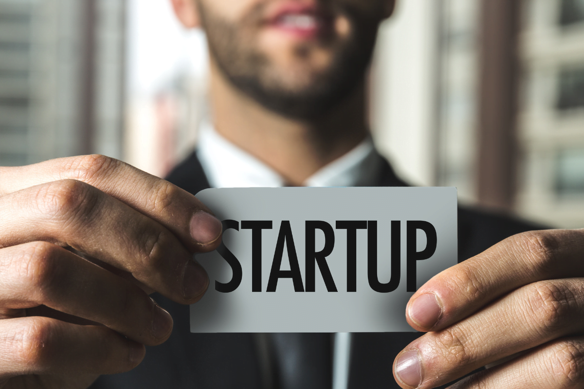 A man holding up a business card with the word startup.