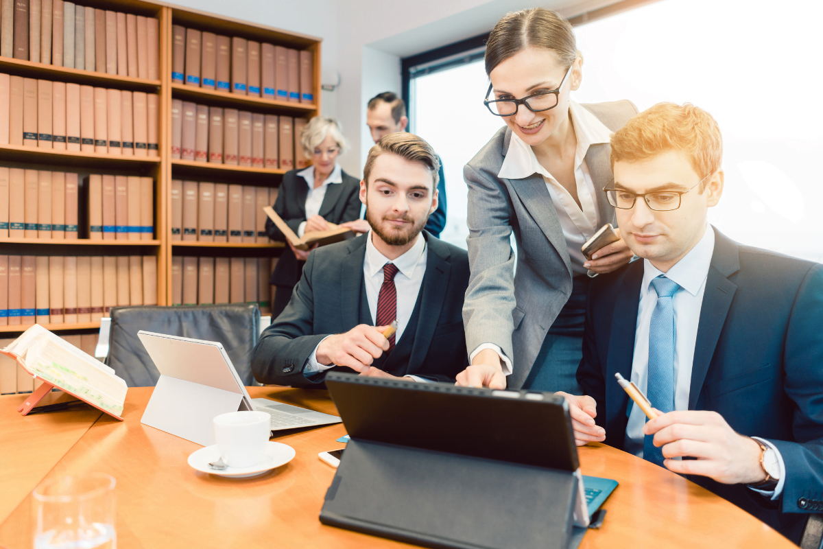 A group of legal professionals looking at a laptop in a conference room, discussing some digital marketing strategies.